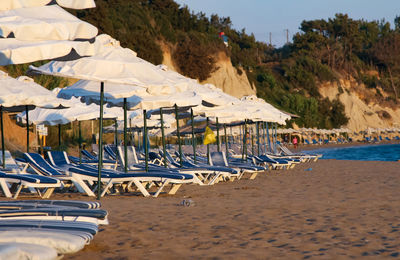 Deck chairs on sand at beach against sky