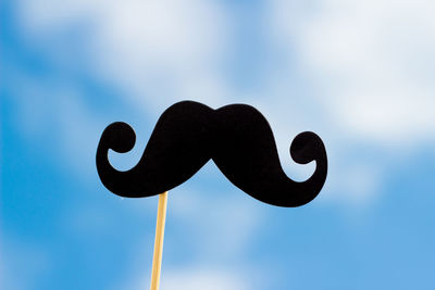 Close-up of mustache prop against sky