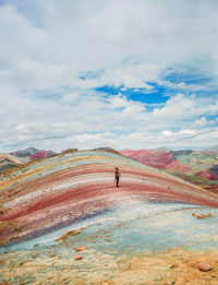 Young woman standing on mountain against cloudy sky