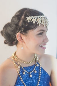 Close-up of smiling woman wearing jewelry against white background