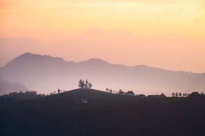 Silhouette trees and mountains against sky during sunset