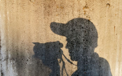 Shadow of man photographing with camera on wall