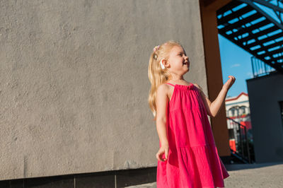 Portrait of young woman standing against wall