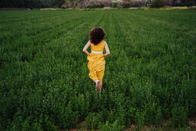 Rear view of woman running amidst plants