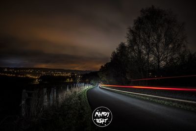 Light trails on road against sky at night