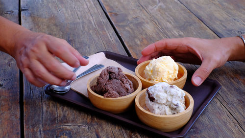 Midsection of person holding ice cream on table