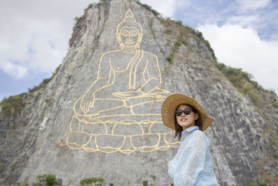 Portrait of woman standing on cross against mountain