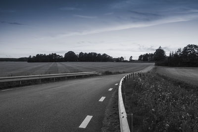 Road by trees against sky
