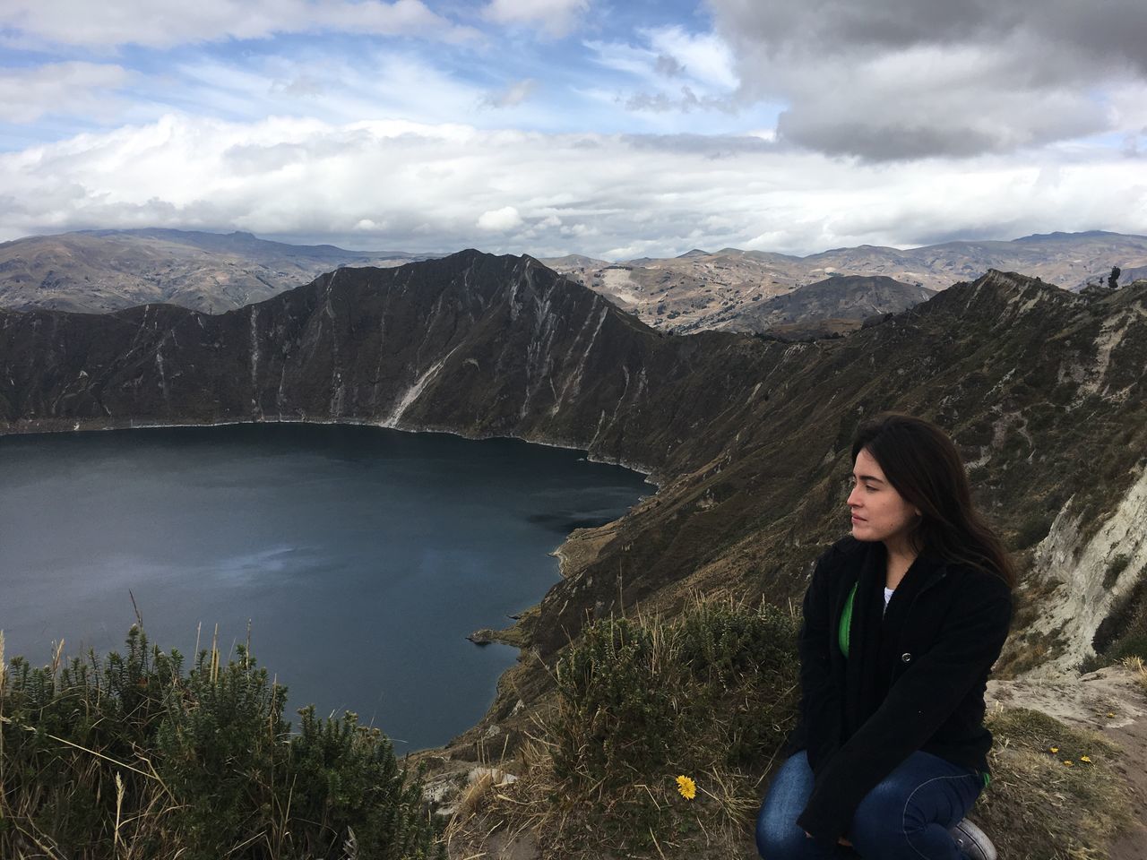 real people, mountain, one person, beauty in nature, nature, leisure activity, casual clothing, lifestyles, scenics, young women, young adult, standing, sky, rock - object, mountain range, outdoors, cloud - sky, sitting, lake, day, water