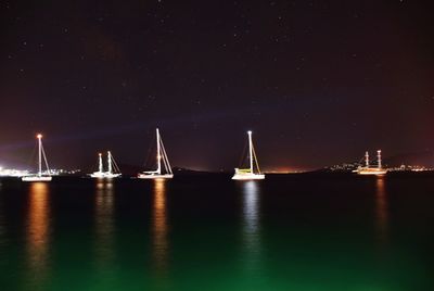 Sailboats sailing in sea against sky at night