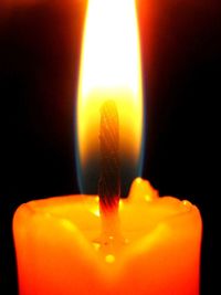 Close-up of lit candle against black background