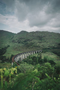 Aerial view of green landscape and arch bridge against cloudy sky