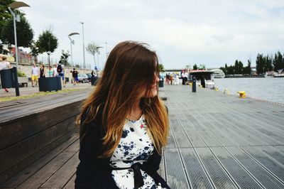 Young woman sitting on promenade by sea