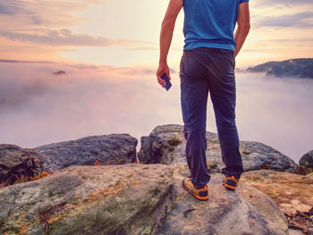 Hiker takes selfie photo, fall nature adventure. man on mountain sumit. daybreak above milky fog