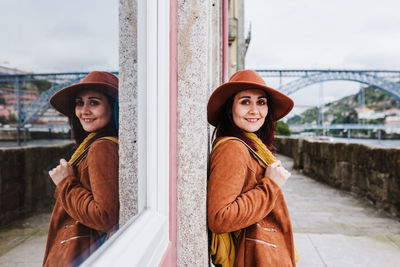 Portrait of beautiful young woman standing against wall