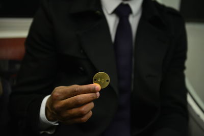 Midsection of businessman holding badge with number 40