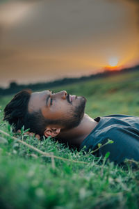 Laying on ground of grasses and the sun sets