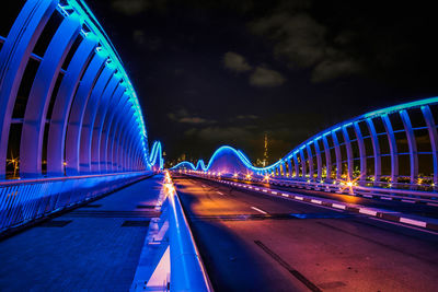 Illuminated footbridge against sky at night