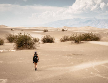 Rear view of man walking on desert against sky