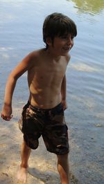 Full length of shirtless boy standing at beach