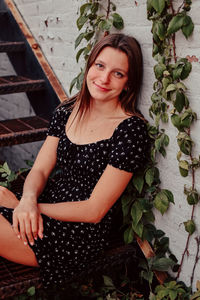 Portrait of beautiful young woman sitting on tree