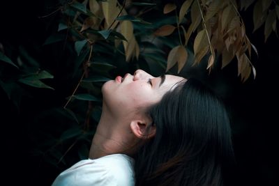 Side view of young woman with eyes closed by plants