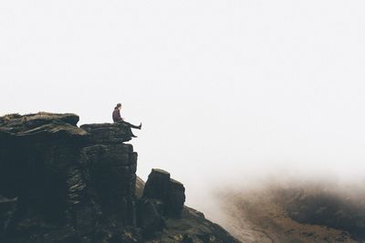 Man on rock against sky