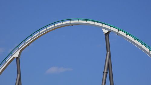 Low angle view of rollercoaster against clear blue sky