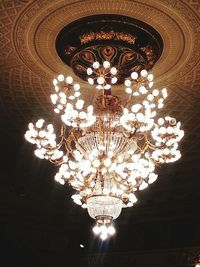 Low angle view of illuminated chandelier hanging on ceiling