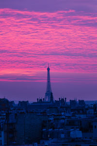 Eiffel tower in city against cloudy dramatic sky during sunset