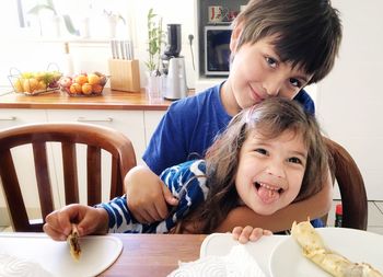 Cute siblings having food at table