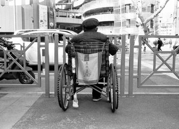 Rear view of man sitting on street in city