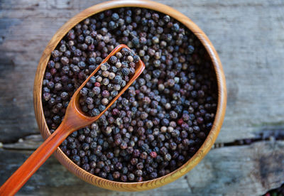 High angle view of black peppercorn in bowl on wooden table