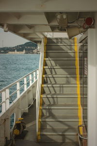 Staircase by sea against yellow sky