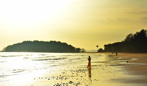 Silhouette person standing on beach against sky during sunset