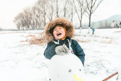 Portrait of young woman standing on snow covered field