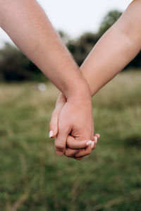 Close-up of couple holding hands outdoors against blurred background