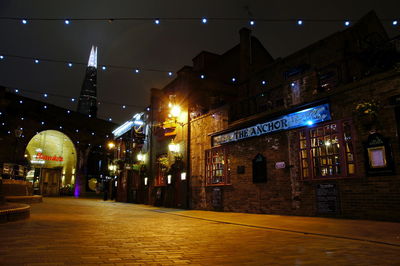 Illuminated street amidst buildings in city at night