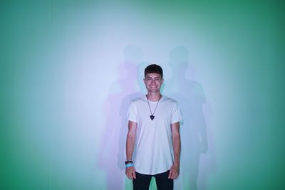 Portrait of young man standing against blue wall