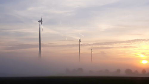 Wind turbine against sky during sunset