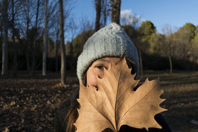 Close-up portrait of young woman holding leaf