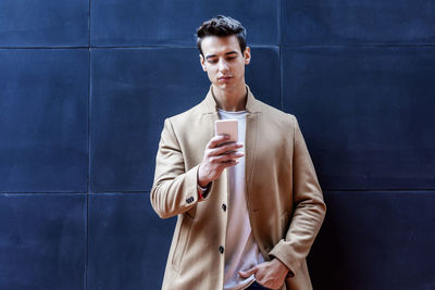 Portrait of young man standing against wall