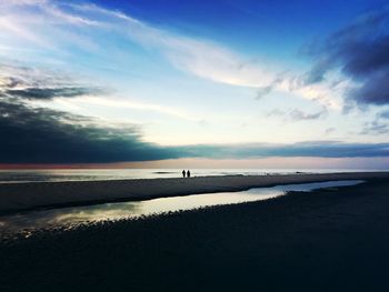 Scenic view of beach against cloudy sky