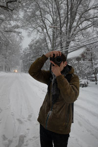 Man photographing on snow covered tree