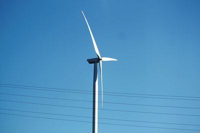 Low angle view of wind turbine against clear blue sky