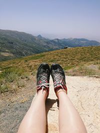Low section of woman on mountain against sky