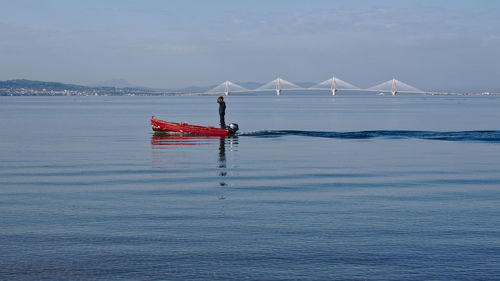 Man standing on speedboat at sea against sky