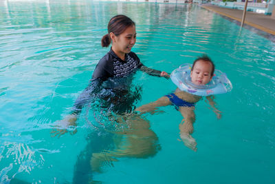 Mother and baby boy with inflatable raft swimming in pool