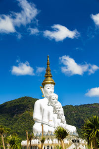 Low angle view of statue by building against sky