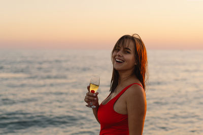 Portrait of young woman standing at beach during sunset